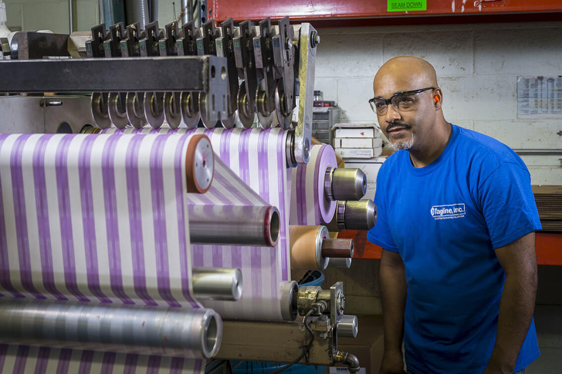 Tagline Inc. factory worker inspects a piece of machinery used for converting